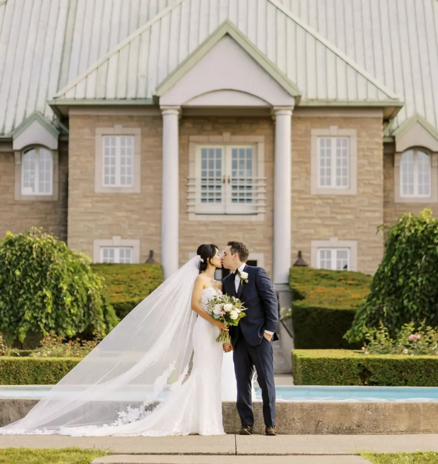 Newlyweds kissing in front of Château des Charmes in Niagara, Ontario.